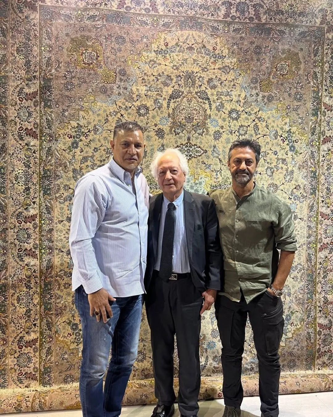 Fußball-Legende Ali Daei mit der Familie Mirzazadeh vor einem feinen Teppich